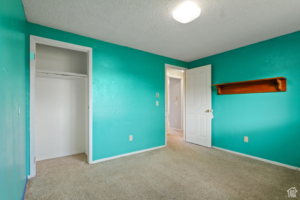 Unfurnished bedroom with a closet, baseboards, carpet flooring, and a textured ceiling