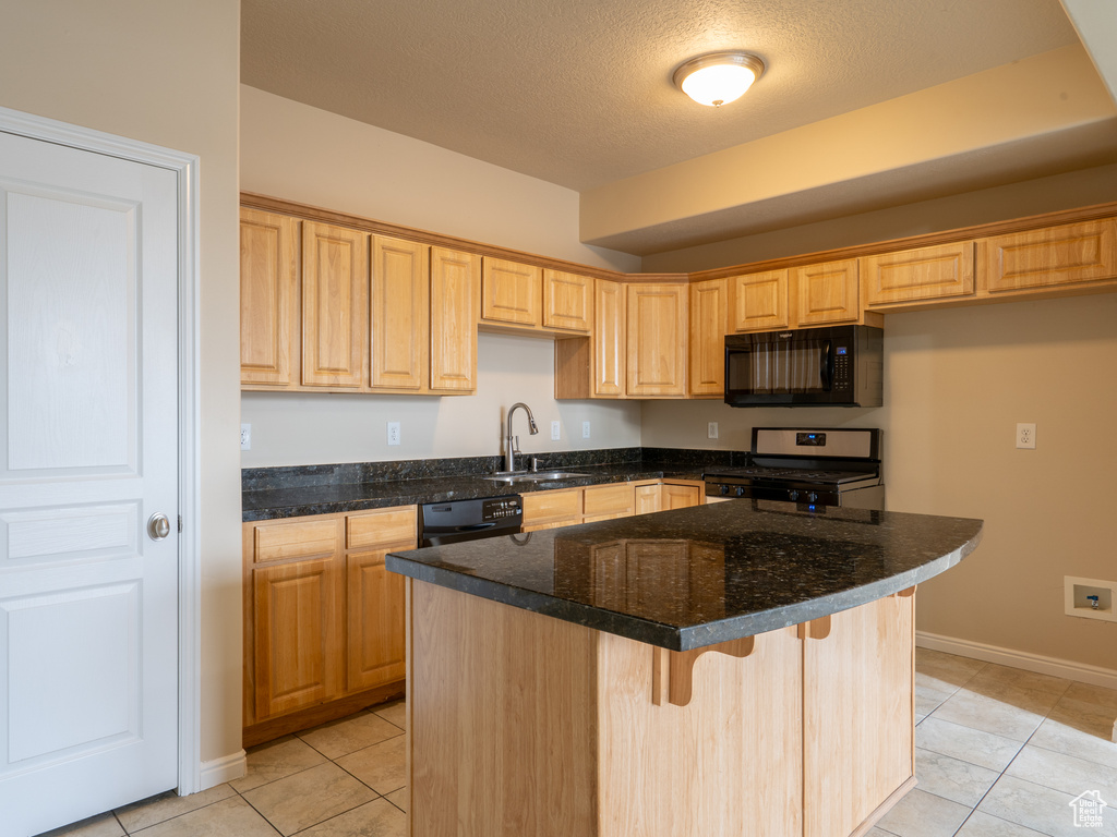 Kitchen with a center island, a kitchen breakfast bar, a textured ceiling, black appliances, and a sink