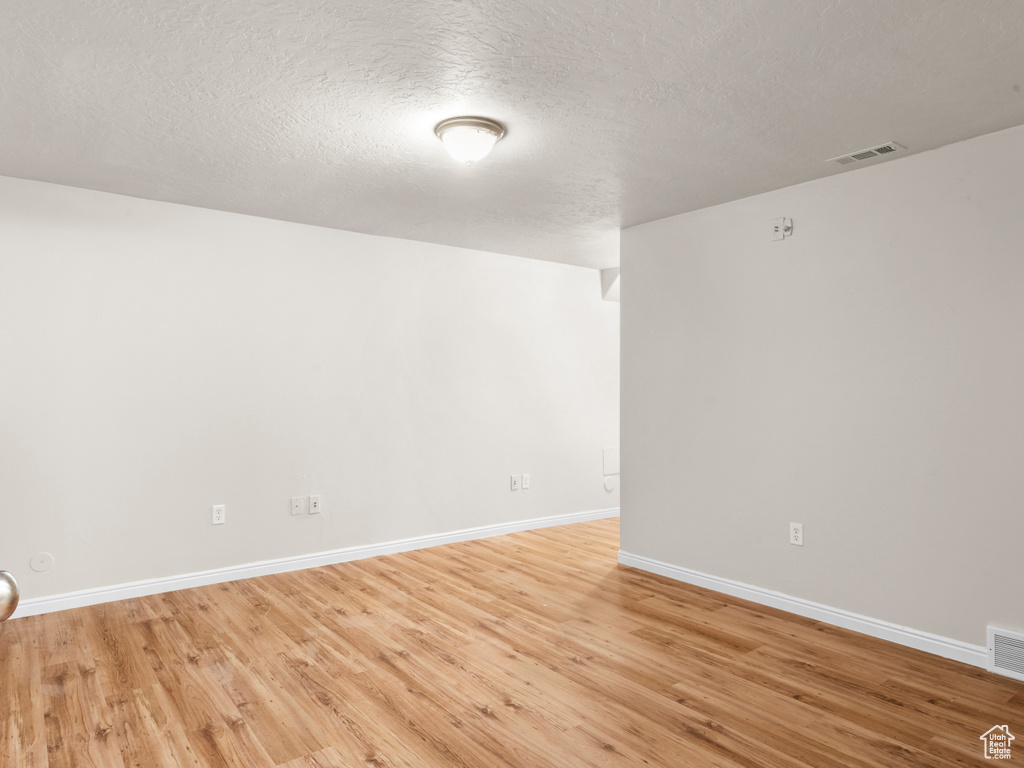 Spare room with baseboards, light wood-style floors, and visible vents
