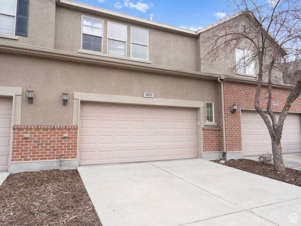 Exterior space with brick siding, driveway, stucco siding, and an attached garage