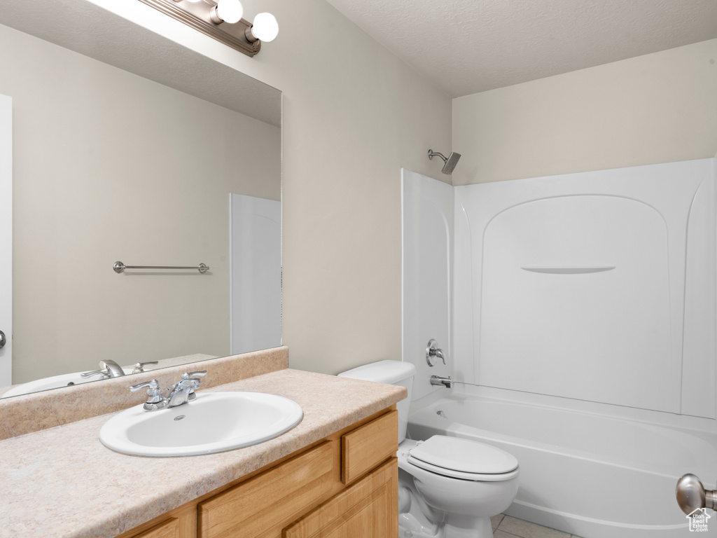 Bathroom with shower / bathing tub combination, vanity, tile patterned flooring, toilet, and a textured ceiling