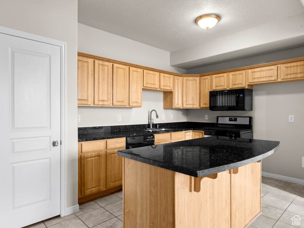 Kitchen with a kitchen breakfast bar, a textured ceiling, a sink, light tile patterned flooring, and black appliances