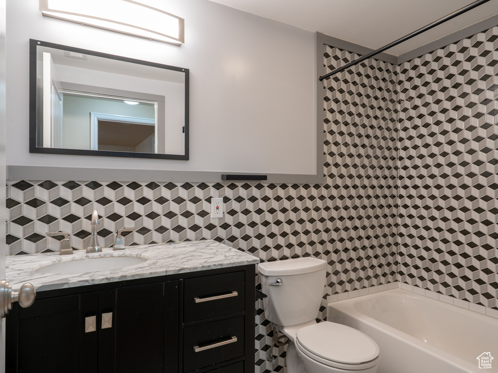Full bath featuring vanity, a bathing tub, a shower, tile walls, and toilet