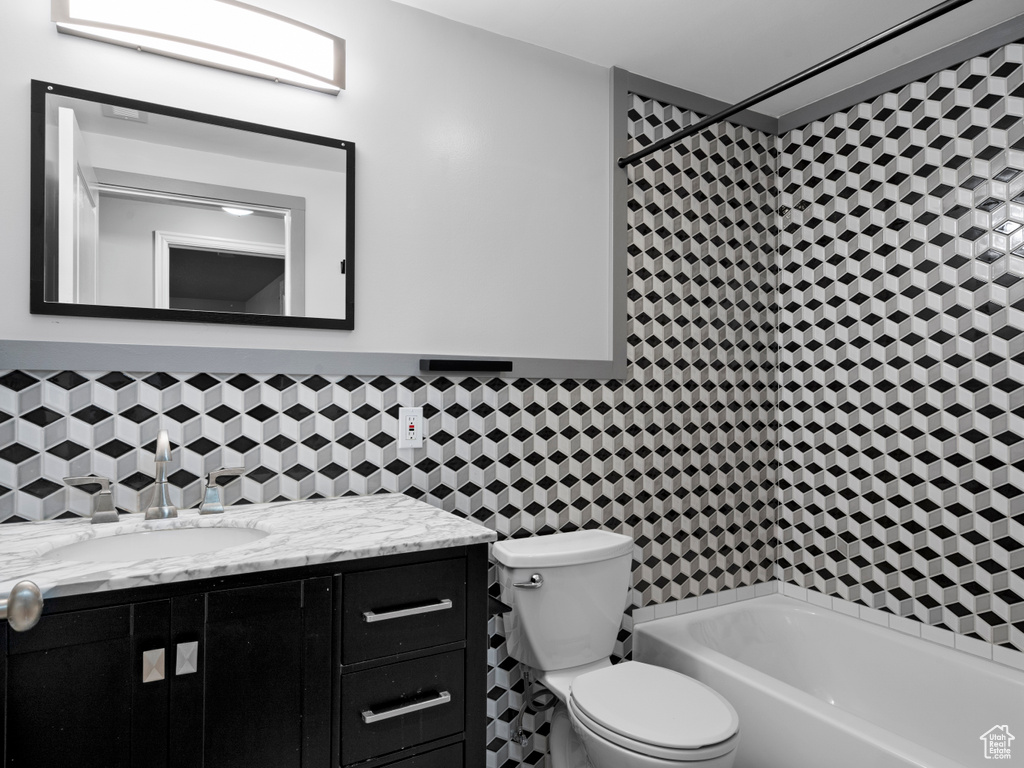 Full bath with tile walls, a bathing tub, a shower, toilet, and vanity