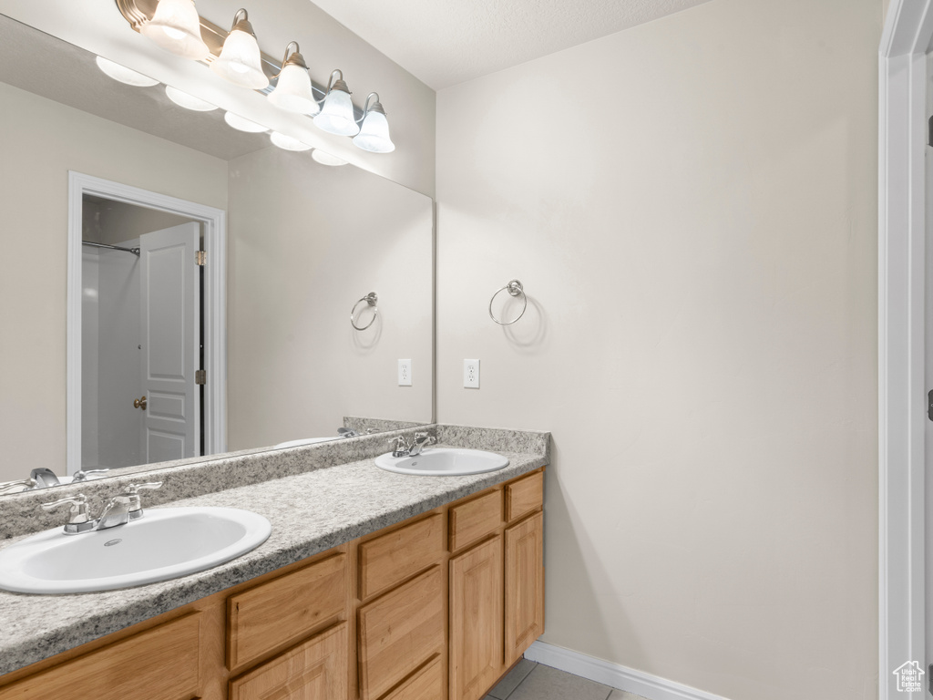 Bathroom featuring baseboards, double vanity, a sink, and tile patterned flooring