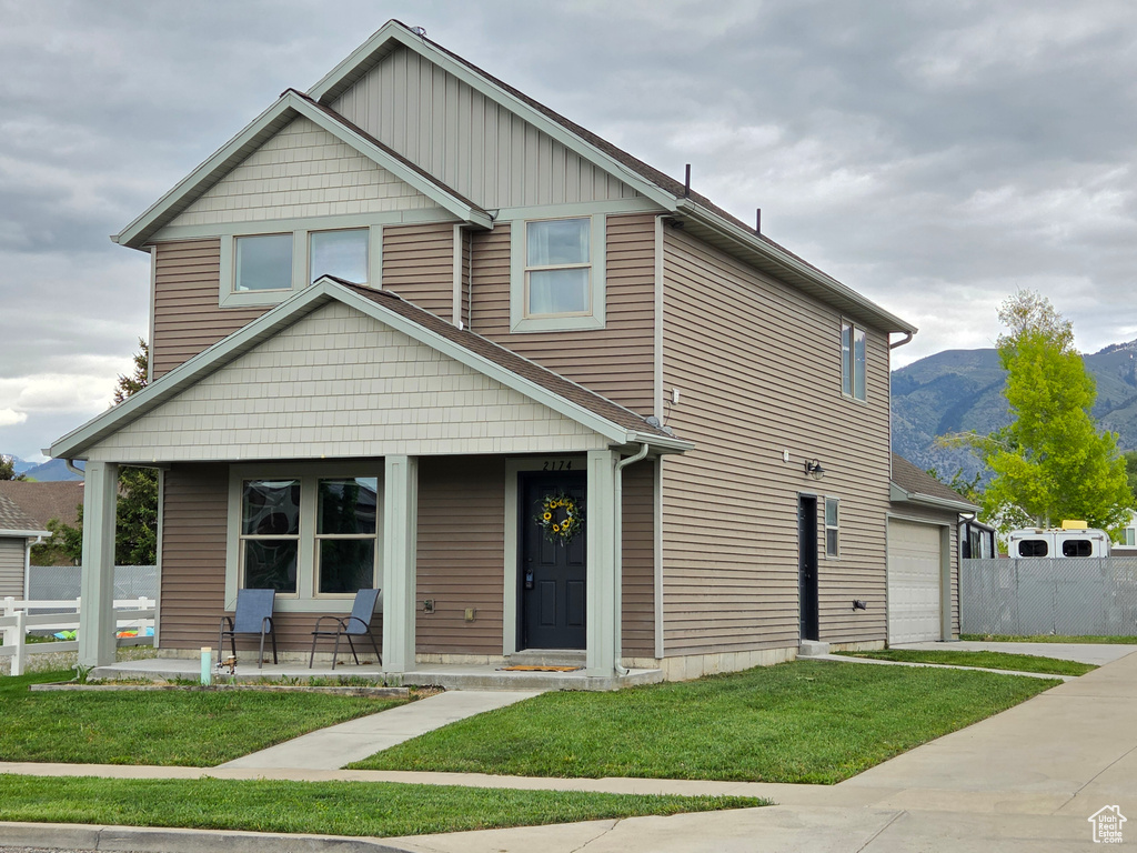 View of front facade featuring covered porch, driveway, a mountain view, and an attached garage