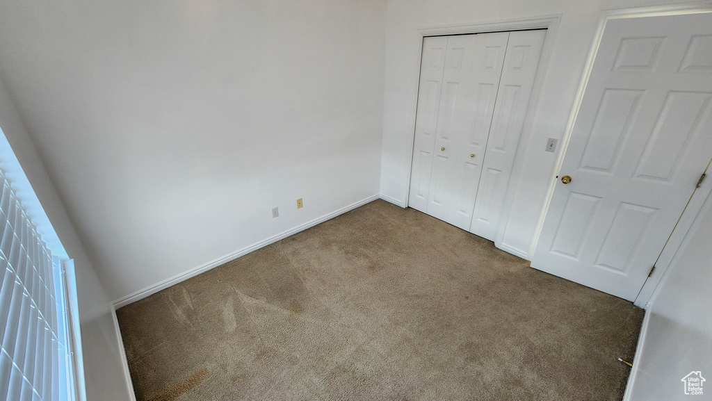 Unfurnished bedroom with a closet, baseboards, and carpet