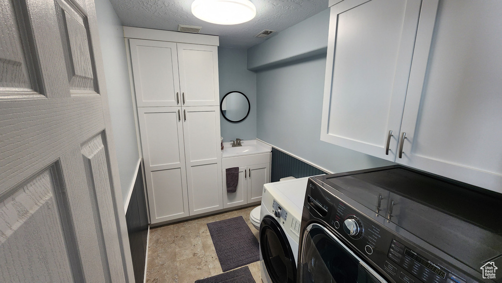 Washroom featuring a sink, visible vents, cabinet space, and a textured ceiling