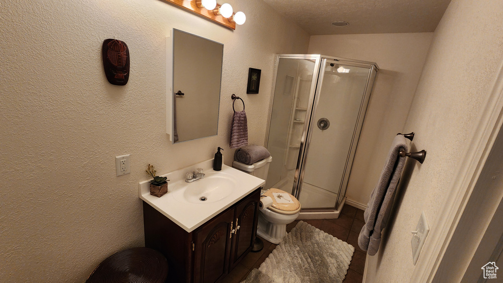 Full bath with toilet, a stall shower, vanity, and a textured wall