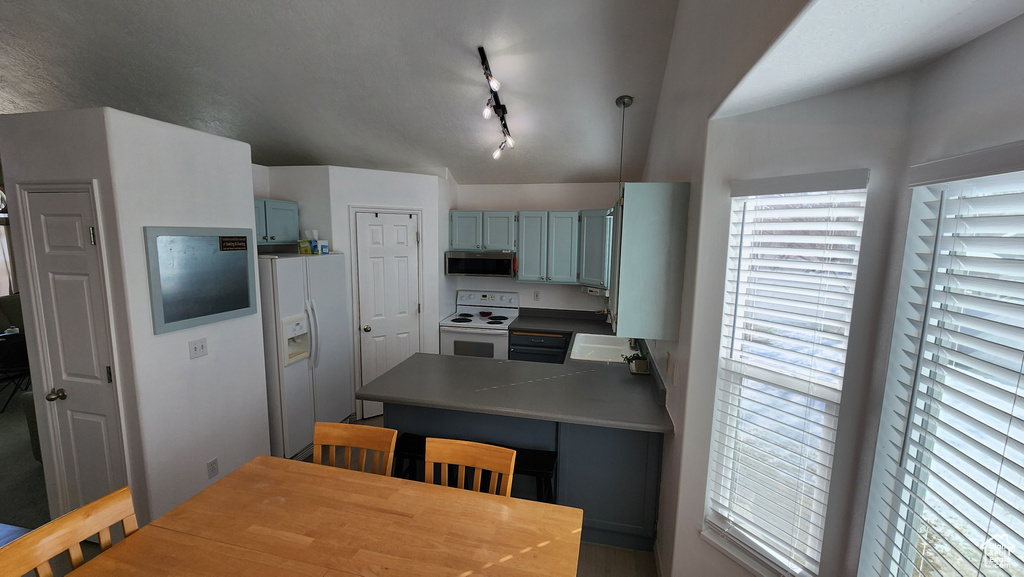 Kitchen with white appliances, a peninsula, blue cabinetry, a sink, and rail lighting