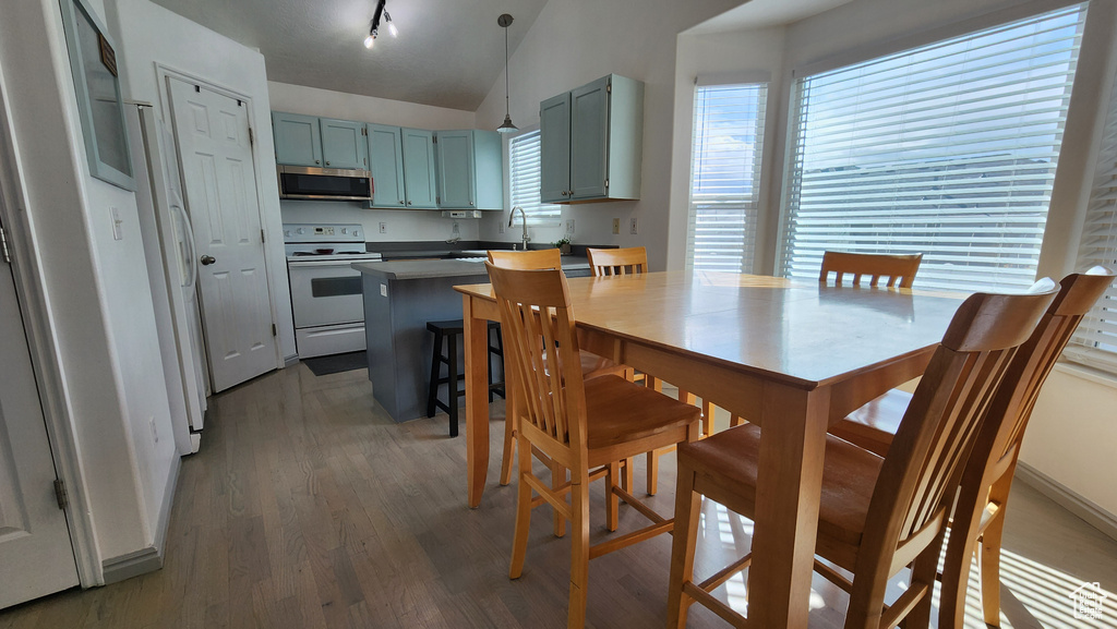 Dining space featuring vaulted ceiling, light wood-style floors, and track lighting