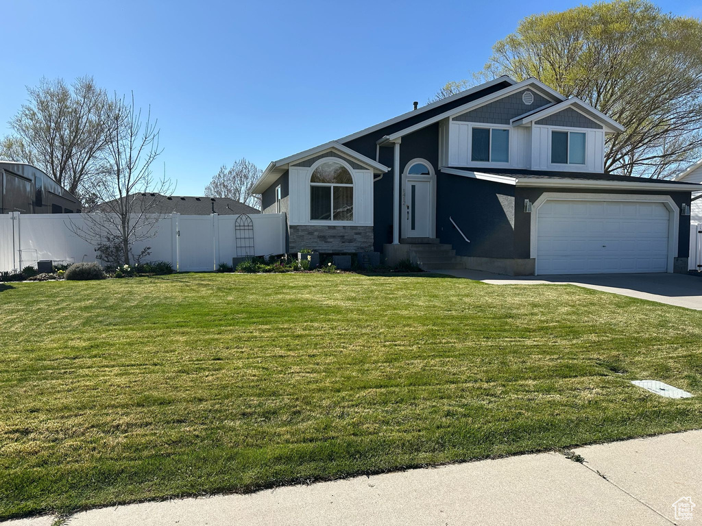 View of front of property with driveway, a gate, fence, a front lawn, and a garage