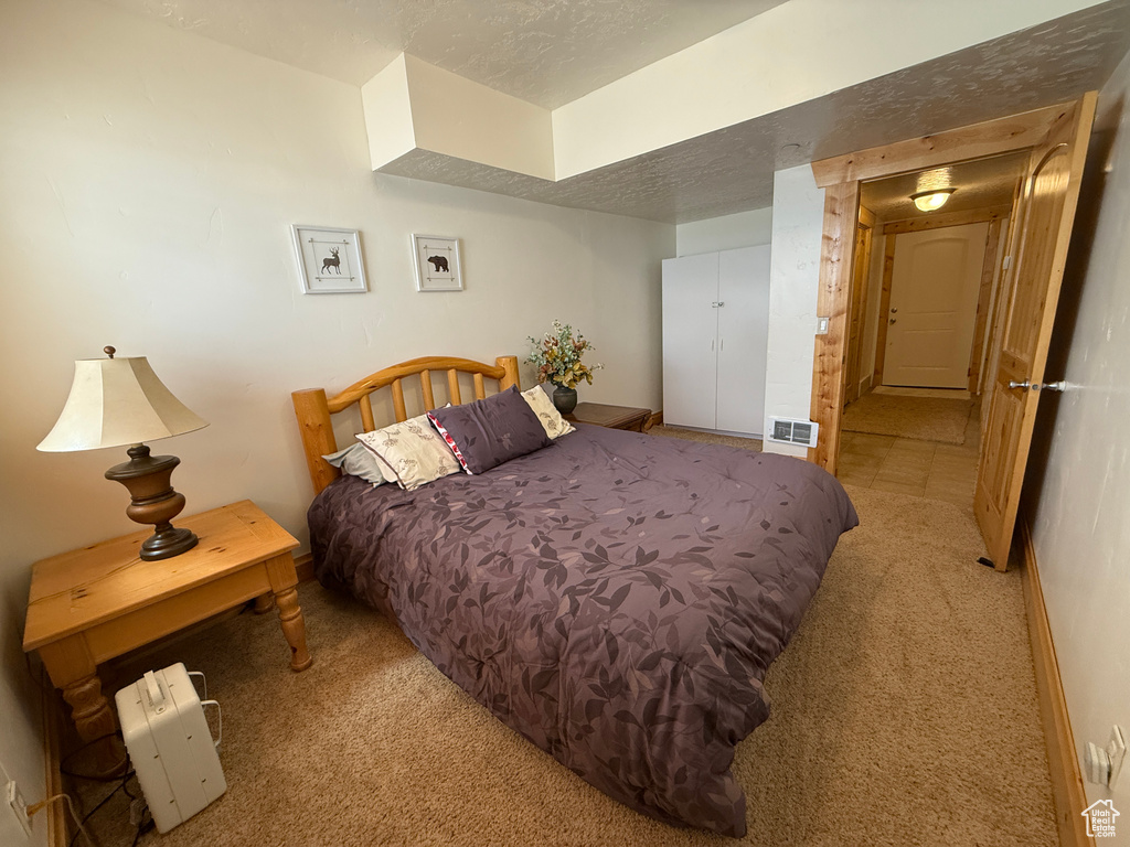 Bedroom with carpet flooring, a textured ceiling, and baseboards