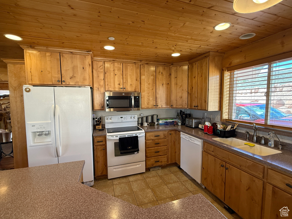 Kitchen featuring white appliances, a sink, wooden ceiling, dark countertops, and recessed lighting