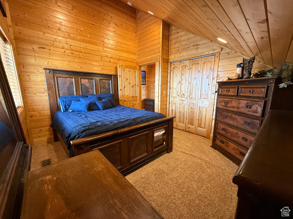 Bedroom with lofted ceiling, wood walls, light carpet, and wood ceiling