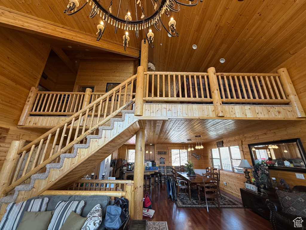 Living area with a high ceiling, a chandelier, wooden walls, wooden ceiling, and stairway