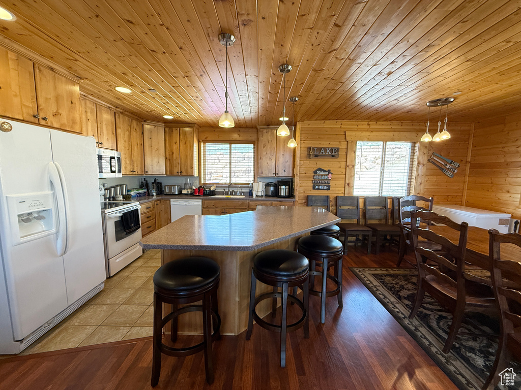 Kitchen featuring white appliances, a sink, wood ceiling, wood finished floors, and a breakfast bar area