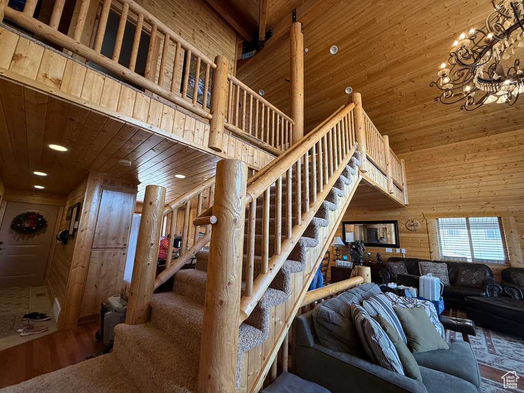 Stairs with wooden ceiling, wood finished floors, wood walls, a chandelier, and a towering ceiling