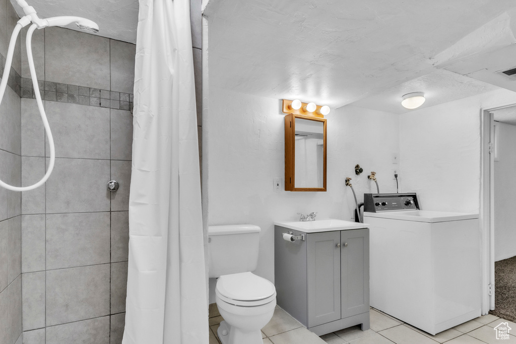 Full bath featuring washer / dryer, vanity, tile patterned flooring, and tiled shower