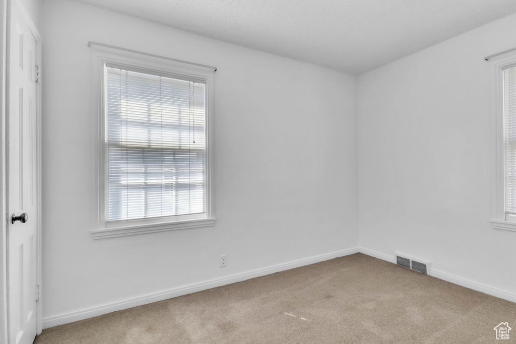 Carpeted spare room featuring baseboards
