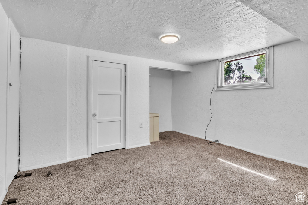 Basement with carpet, a textured ceiling, and baseboards