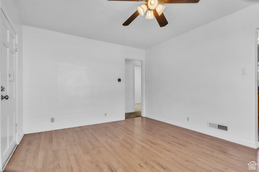 Spare room with ceiling fan, light wood-type flooring, and baseboards