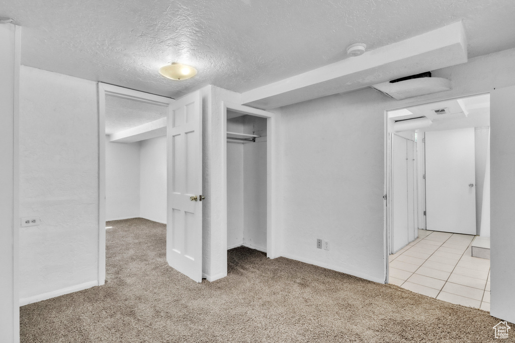 Unfurnished bedroom featuring carpet floors, a textured ceiling, and a closet