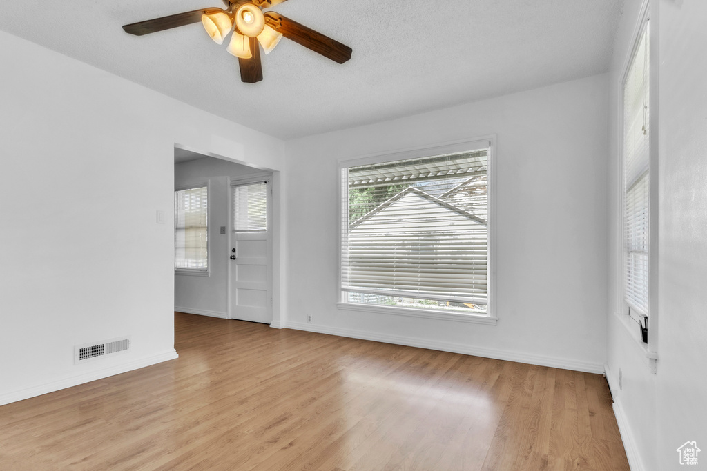 Unfurnished room with wood finished floors, a ceiling fan, and baseboards