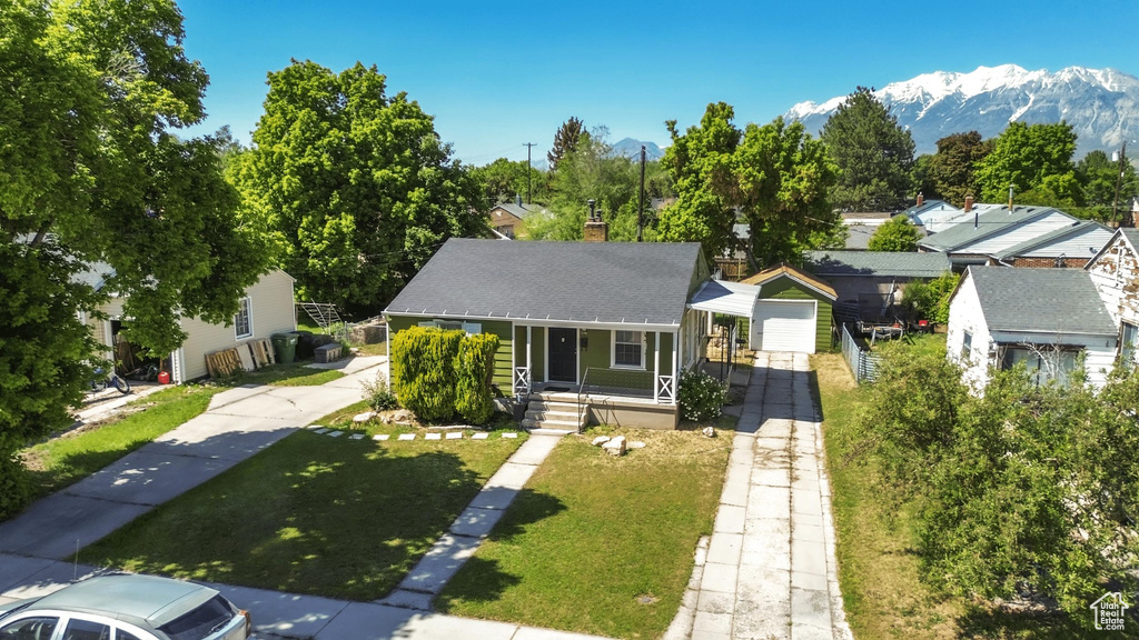 Bungalow with a porch, a chimney, a mountain view, a front yard, and a shingled roof