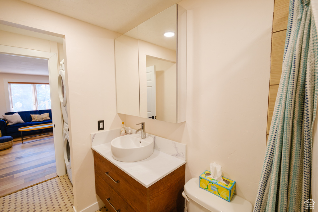 Ensuite bathroom with vanity, toilet, stacked washer / drying machine, and connected bathroom