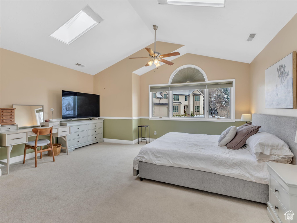 Carpeted bedroom with visible vents, vaulted ceiling with skylight, baseboards, and ceiling fan