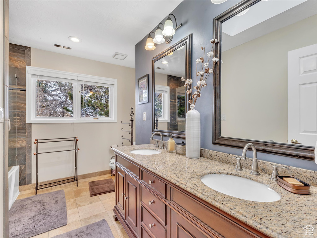 Full bathroom with double vanity, visible vents, a shower, and a sink