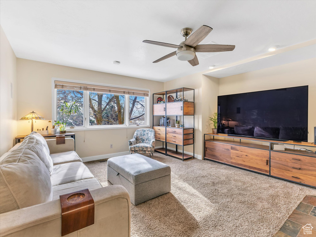 Carpeted living area with baseboards and a ceiling fan