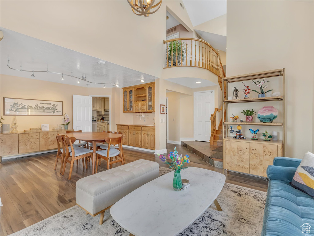 Living room featuring baseboards, stairway, rail lighting, an inviting chandelier, and wood finished floors