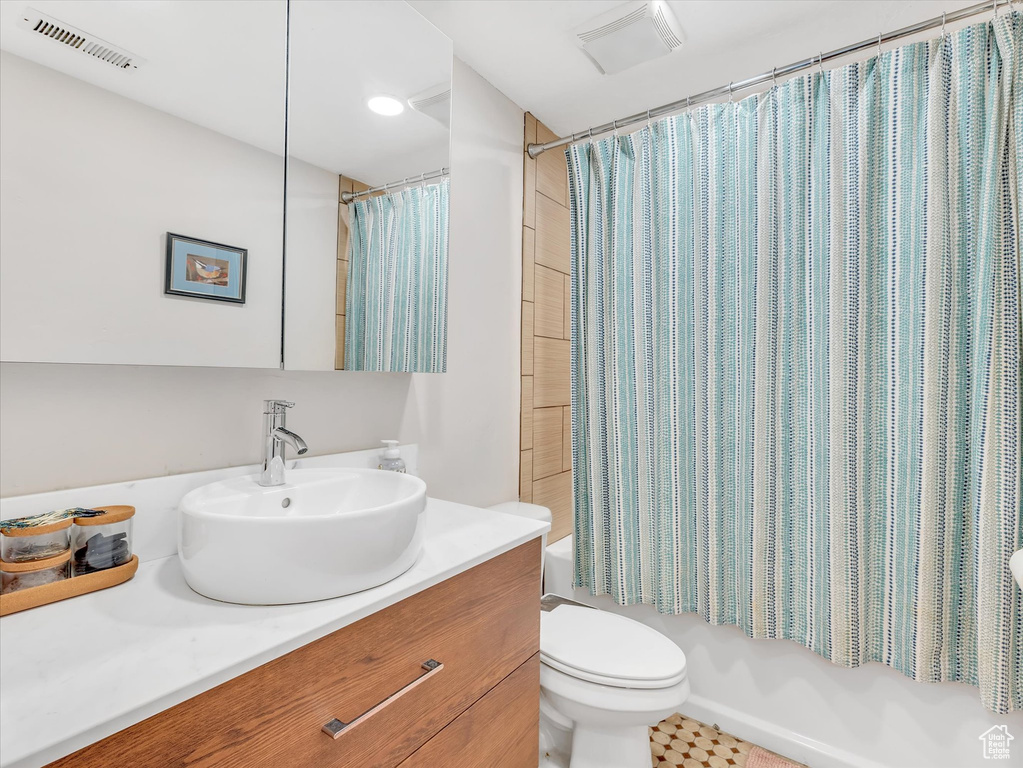 Bathroom with visible vents, shower / tub combo with curtain, vanity, and toilet