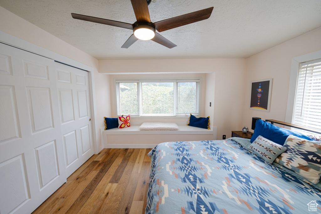 Bedroom with a closet, light wood-style floors, ceiling fan, and a textured ceiling