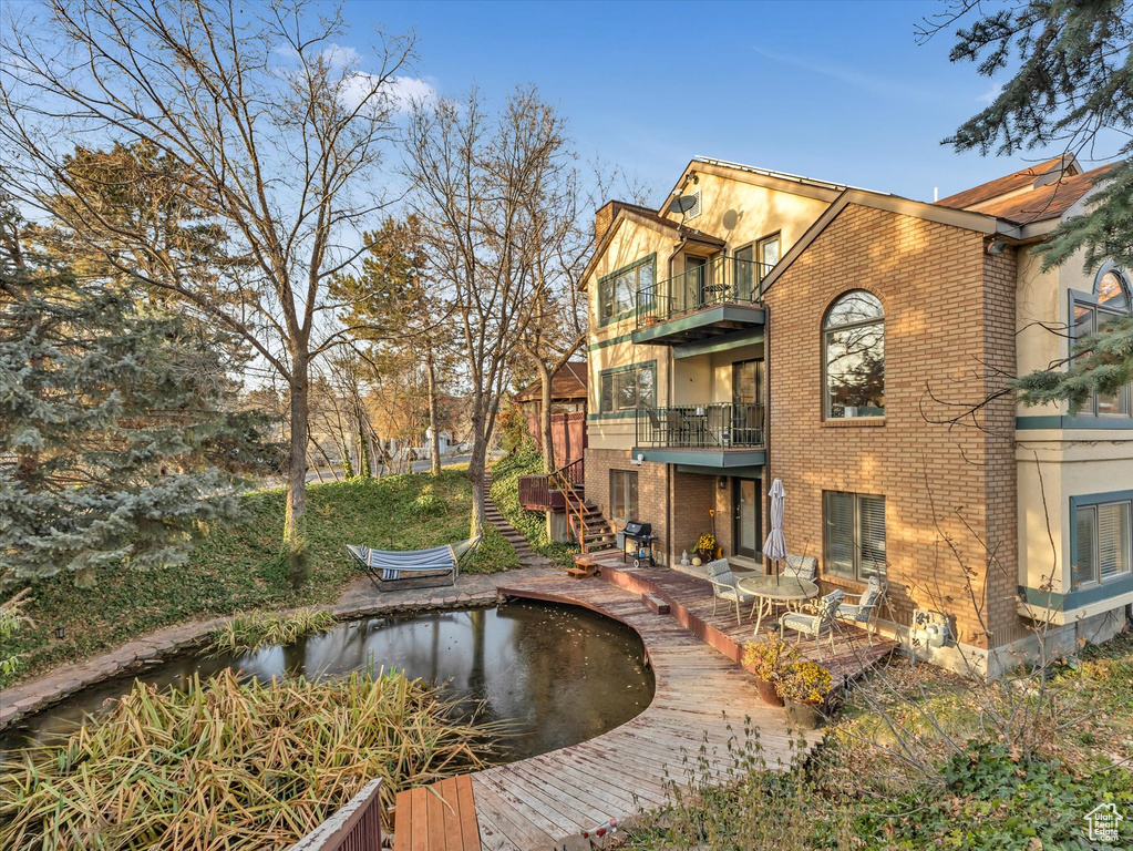 Rear view of property with stairway, a balcony, and brick siding