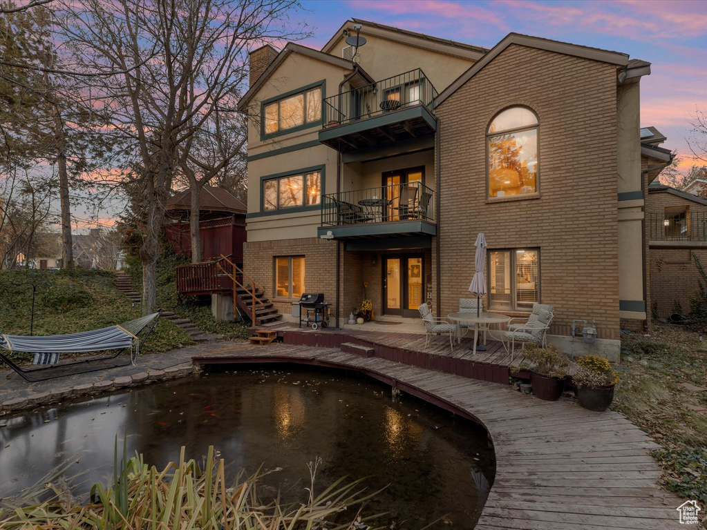 Rear view of property with a balcony, a chimney, stucco siding, a patio area, and brick siding