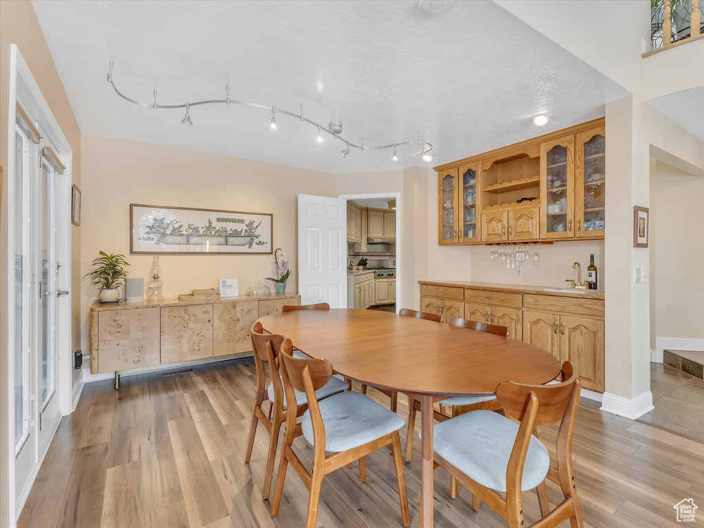 Dining room with indoor wet bar, baseboards, light wood-style flooring, and track lighting