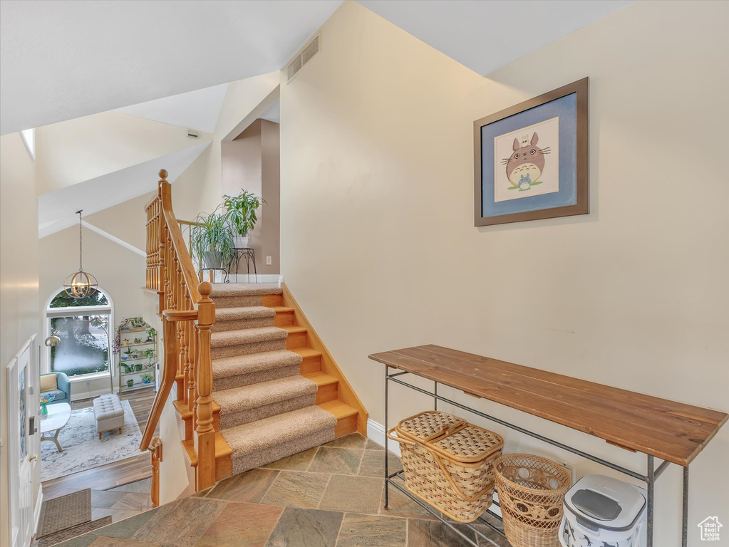 Stairs with visible vents, baseboards, high vaulted ceiling, and stone tile flooring