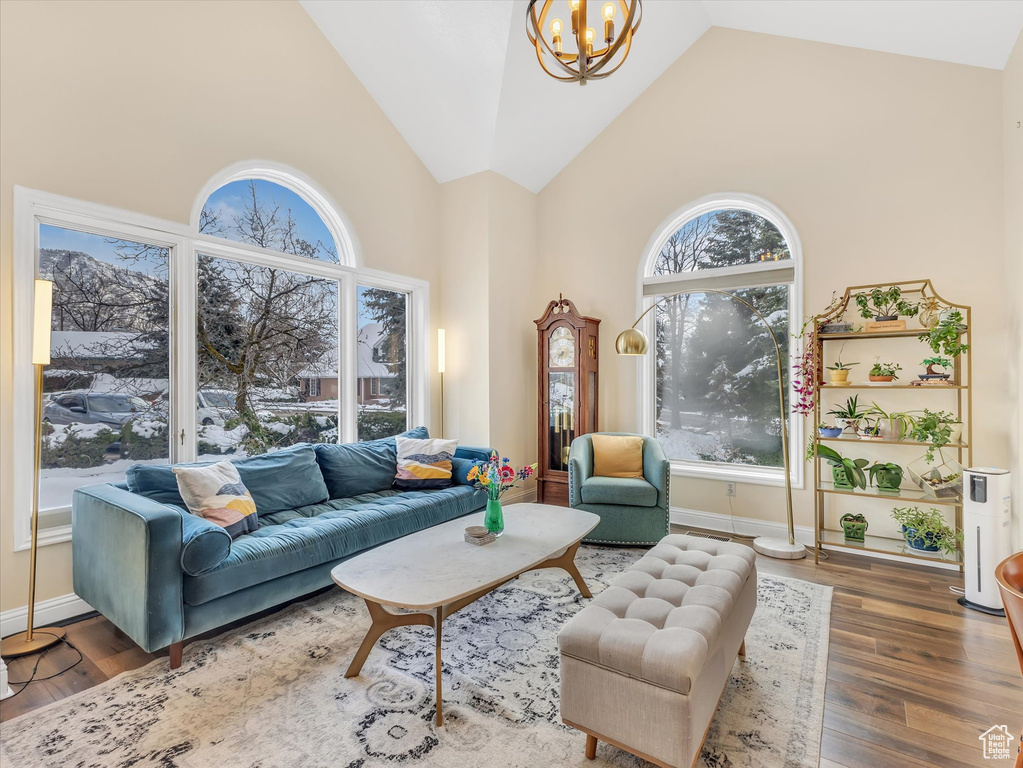 Living room featuring baseboards, high vaulted ceiling, an inviting chandelier, and wood finished floors