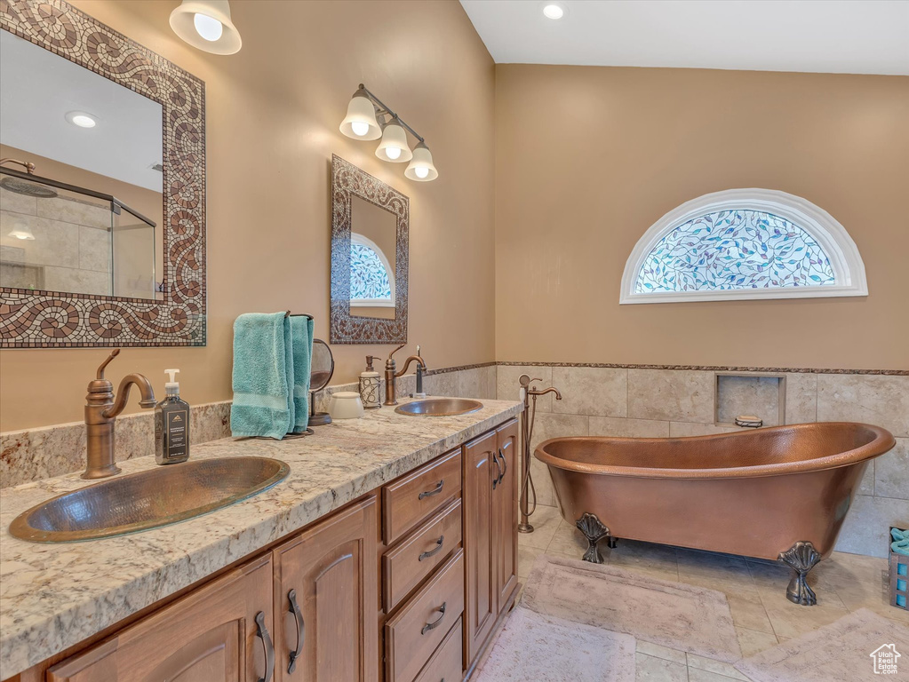 Bathroom with double vanity, a stall shower, tile walls, and a sink