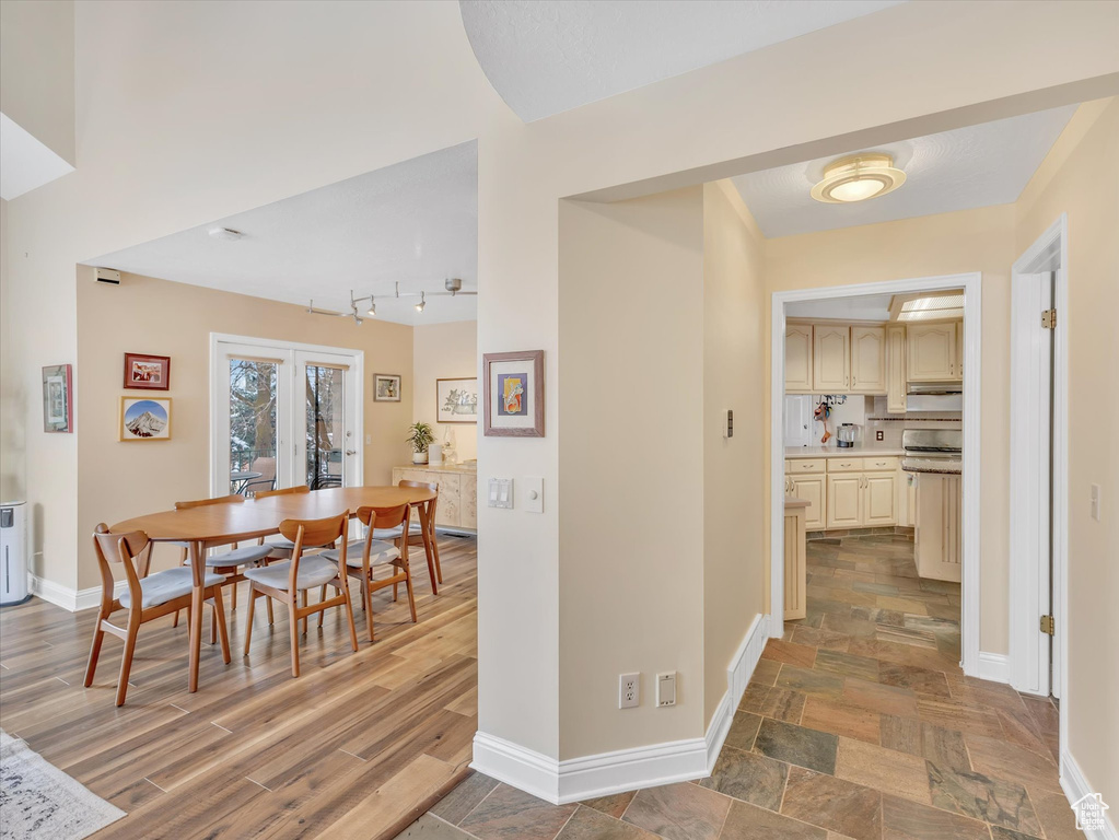 Dining room with french doors, baseboards, wood finished floors, and track lighting