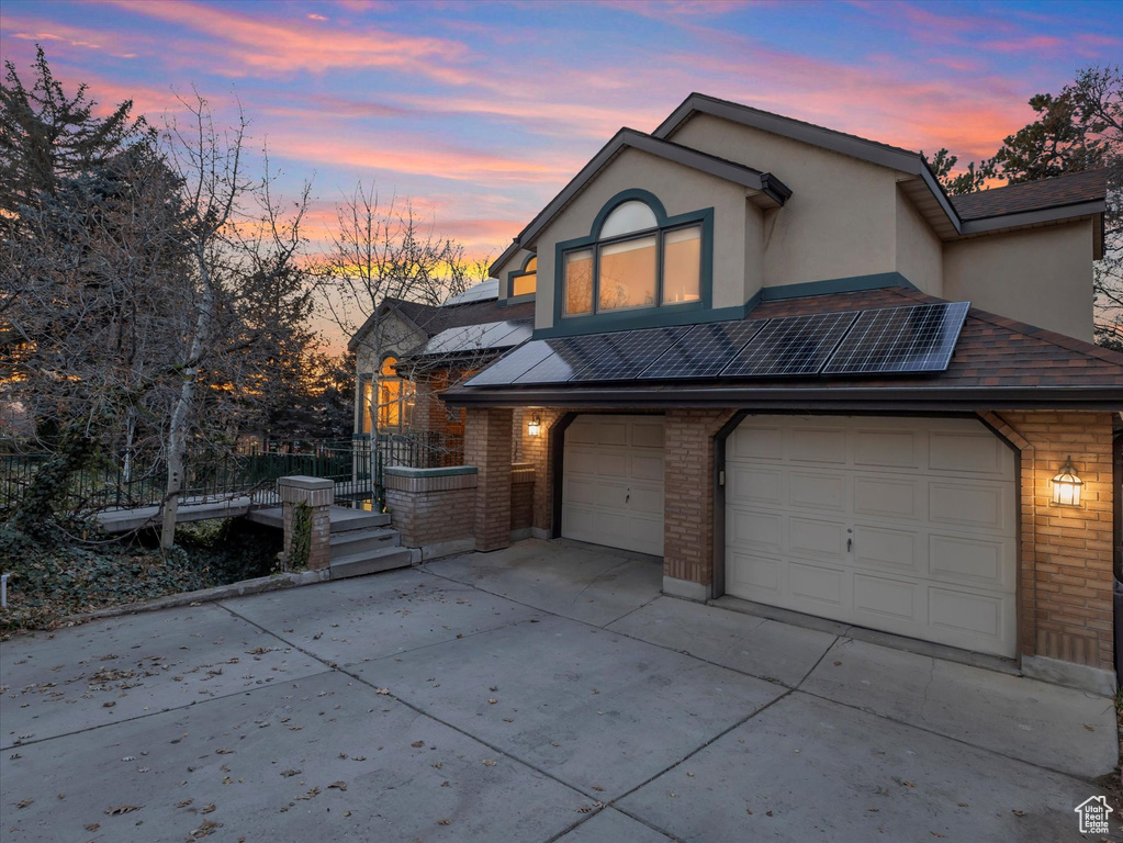 View of front of property featuring concrete driveway, a garage, brick siding, and stucco siding