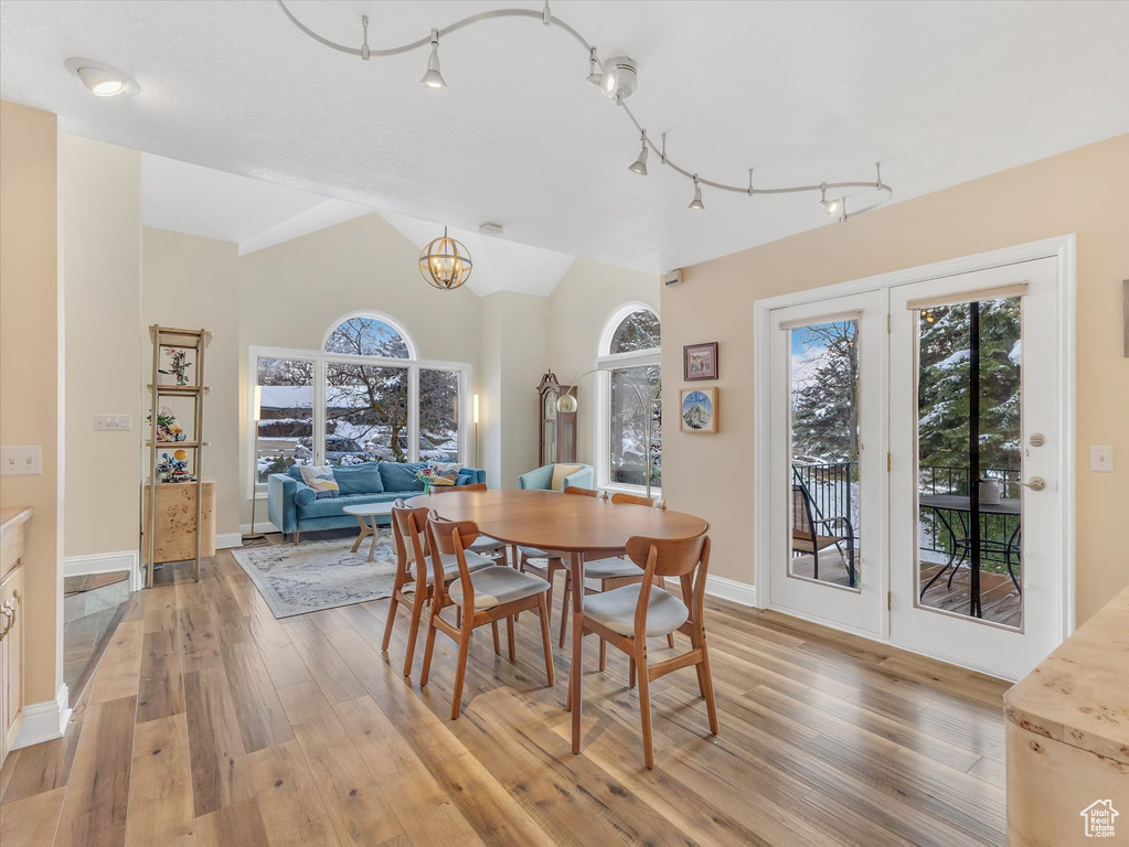 Dining room featuring an inviting chandelier, lofted ceiling, baseboards, and light wood finished floors