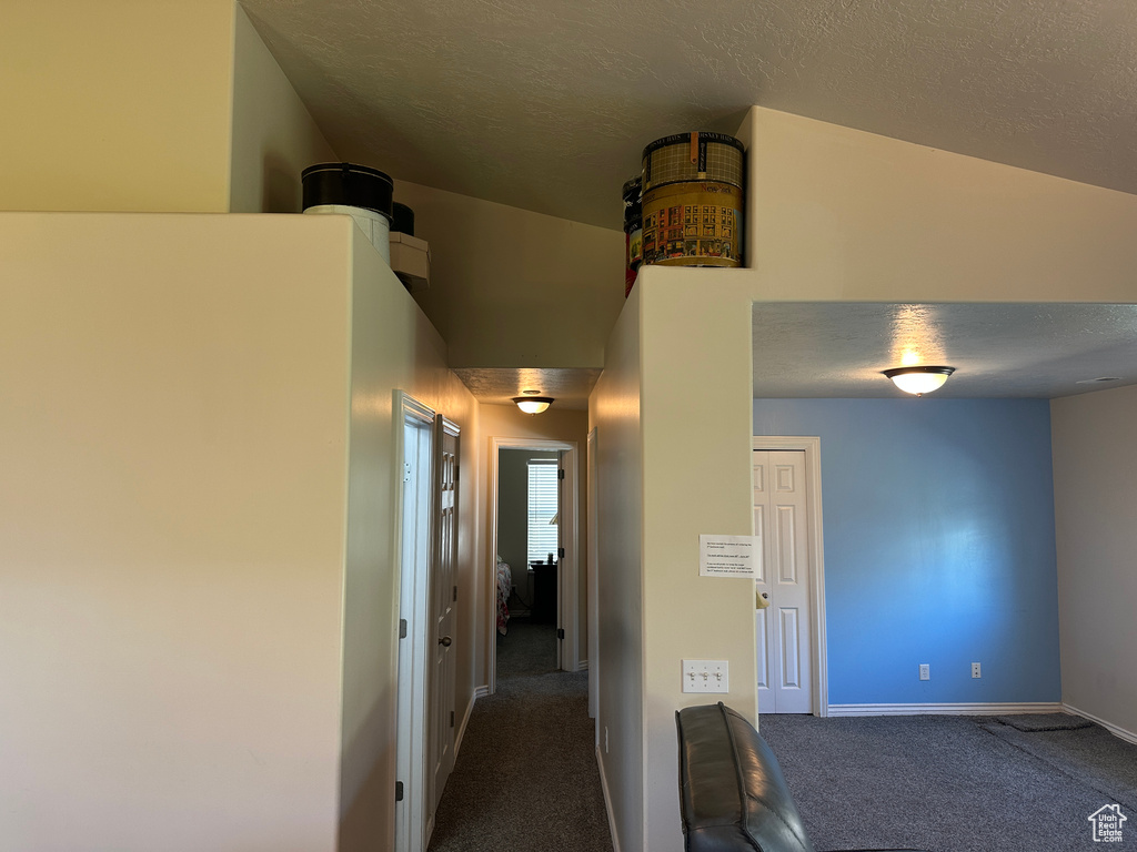 Hallway with carpet floors, a textured ceiling, and baseboards