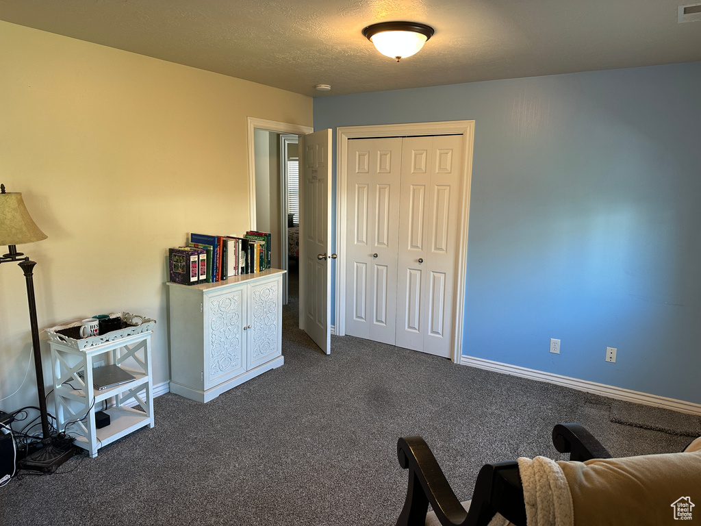 Bedroom featuring dark carpet, a closet, baseboards, and a textured ceiling