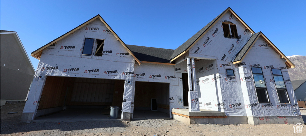 Property under construction featuring gravel driveway and a garage
