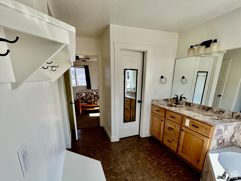 Full bath featuring a textured ceiling, a bath, and vanity