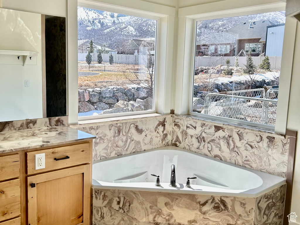 Bathroom featuring vanity, a garden tub, a wealth of natural light, and a textured ceiling